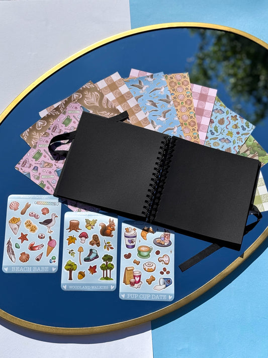black 200gsm cardstock page scrapbook. 9 scrapbook papers themed to days out with your dog, plus 3 matching sticker sheets. the themes are pup cup date, a day at the beach with your dog and a woodland walk with your dog.